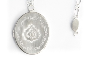 Patricia Sullivan: “Widget Locket #5: Homage to Vanity” (front detail and clasp).  Chased sterling silver, archival paper, Plexiglas, sterling chain/clasp. 19  7/8" x 2  5/16" x 5/16", 2014. Photo: P. Sullivan