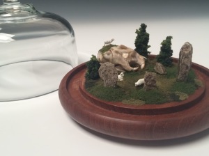 Cate Richards, "Henge I". Antique glass with teak base, artificial plant material, stone, bone, railroad figurines, 7 ½” x 6”, 2015.